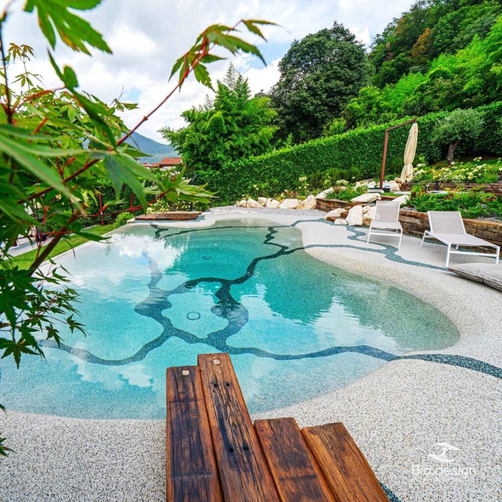 Biodesign Pool mit Strandeinstieg und Mosaikmuster im Garten